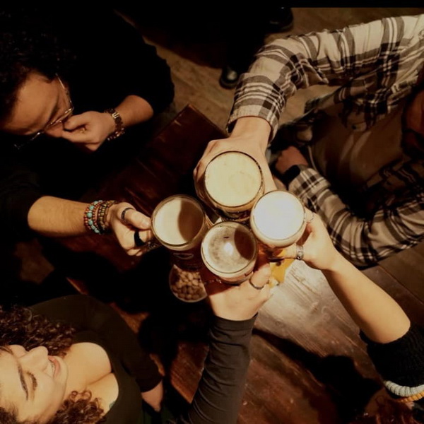 Friends clinking beer mugs over the table