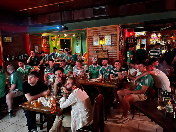 Fans in green jerseys watching the match